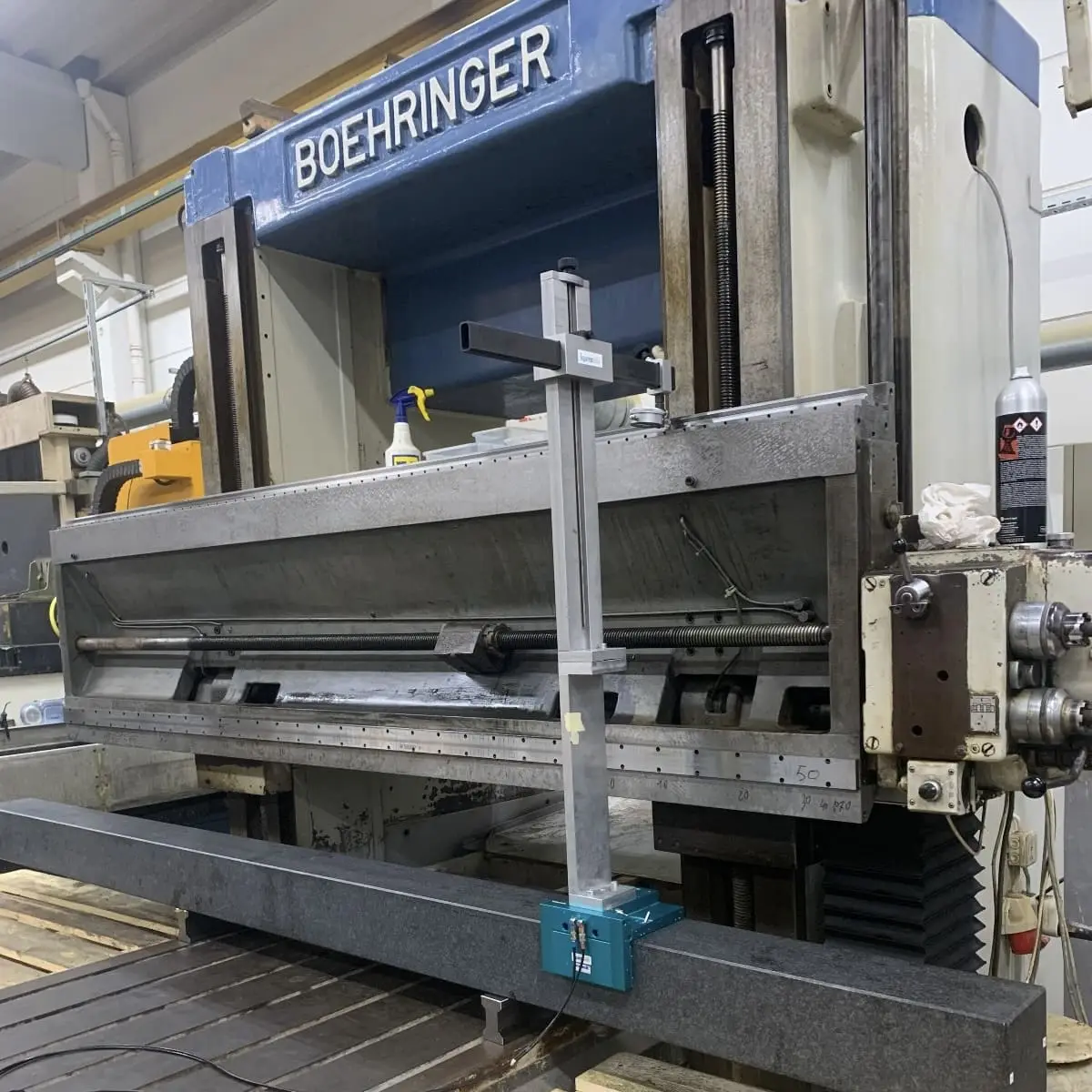 Drehmaschine mit dem Schriftzug Boehringer am Spindelstock. Vor dem Bett liegt ein Granitlineal, darauf ein Messstativ mit Ausleger über den Bahnen.